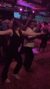 a group of people are dancing in a dark room