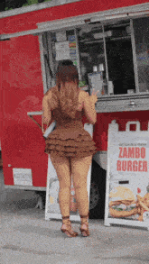 a woman is standing in front of a zambo burger truck
