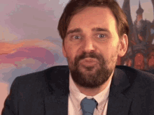 a man with a beard wearing a suit and tie is making a funny face