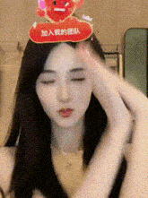 a woman is wearing a sticker on her head that says `` 加入 我 的 团队 '' and making a face .