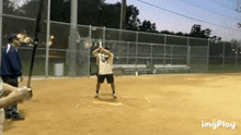 a man is swinging a bat at a baseball while another man watches .