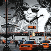 a sign that says inxs on it in front of a large painting of a man
