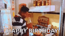 a man is drinking from a cup in a kitchen and the words `` happy birthday '' are written below him .