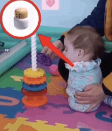 a baby is playing with a stacking toy with an arrow pointing to it