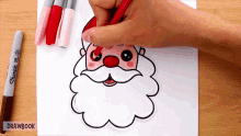 a person is drawing a santa claus head with a red marker