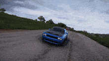 a blue car is driving down a road with trees in the background