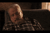 a man in a plaid shirt is sitting in a chair