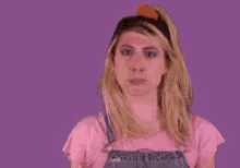 a woman in overalls is making a face in front of a purple background that says sorry