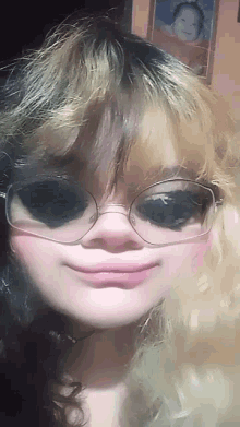 a girl wearing glasses and a wig is smiling for the camera .