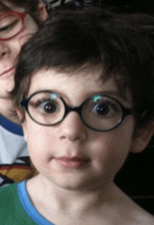 a little boy wearing glasses looks at the camera