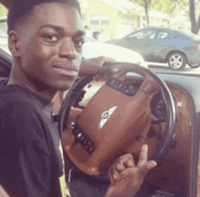 a young man is sitting in a bentley car and holding the steering wheel