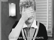 a black and white photo of a woman covering her face with her hand and saying `` me over by the weights '' .