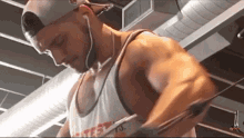 a man wearing a white tank top with the word test on it is lifting a rope