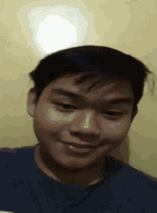 a young man in a blue shirt is smiling and making a face .