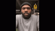 a man with a beard is wearing a beanie and a gray shirt and says what he say fuck me for .