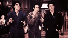 three men in bathrobes are standing in a dark room