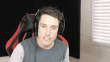 a man wearing headphones is sitting in a red chair in front of a window