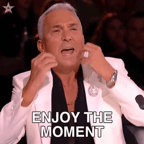 a man in a white suit is making a funny face and says enjoy the moment