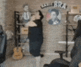 a man is standing in a room with a guitar and a brick wall .