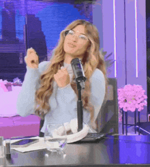 a woman wearing glasses is sitting at a desk with a microphone