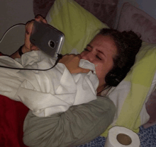 a woman wearing headphones is crying while holding a phone