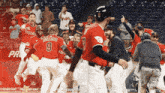 a baseball player with the number 9 on his jersey is surrounded by his teammates