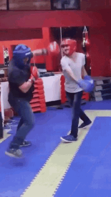 a man wearing a helmet and boxing gloves throws a punch at another man wearing a white shirt