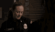 a woman in a police uniform is standing in a dark room .
