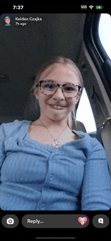 a girl wearing glasses and a blue shirt is sitting in a car with the time 7:37