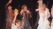 a group of men are standing on a stage with their hands in the air