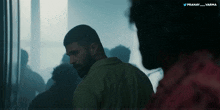 a man with a beard is standing in a dark room with a twitter logo above him that says pranay varma