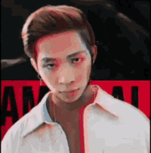 a man in a white shirt is looking at the camera with a red background .