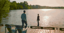 a man and a woman are standing on a dock looking at each other