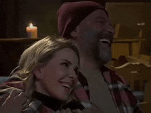 a man and a woman are hugging and smiling in front of a candle