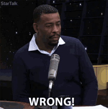 a man sitting in front of a microphone with the word wrong on his face