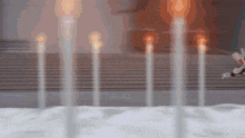 a bunch of candles are lit up in a room with stairs in the background