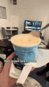 a person holding a cup of ice cream that says " their greed sickens me " on it