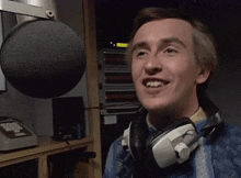 a man wearing headphones and a microphone smiles