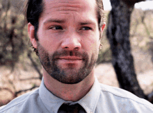 a man with a beard is wearing a light blue shirt and tie