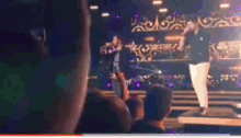 a man is standing on a stage in front of a crowd of people watching a concert .