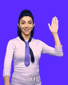 a woman wearing a tie and a white shirt is waving her hand and saying hi