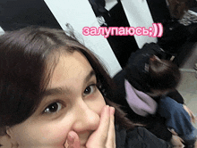 a girl covering her mouth with her hand with a pink sticker that says " залупаюсь " on it