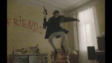 a woman is jumping in the air with a gun in front of a wall that says friends