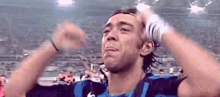 a soccer player is holding his hands up in the air while wearing a blue and black jersey .