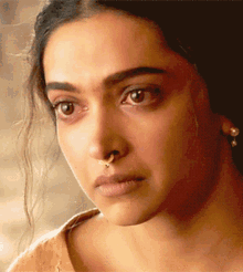 a close up of a woman with a nose ring and earrings