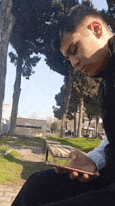 a young man sitting on a bench looking at his phone