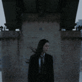 a woman in a suit and tie is standing under a bridge with the number 120 on the side