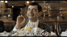 mr bean is eating a hamburger in a restaurant while wearing a white tie .