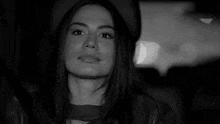 a black and white photo of a woman sitting in the back seat of a car .