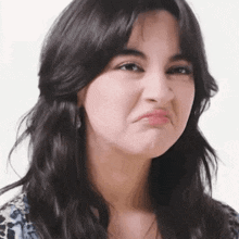 a woman with long hair is making a funny face .